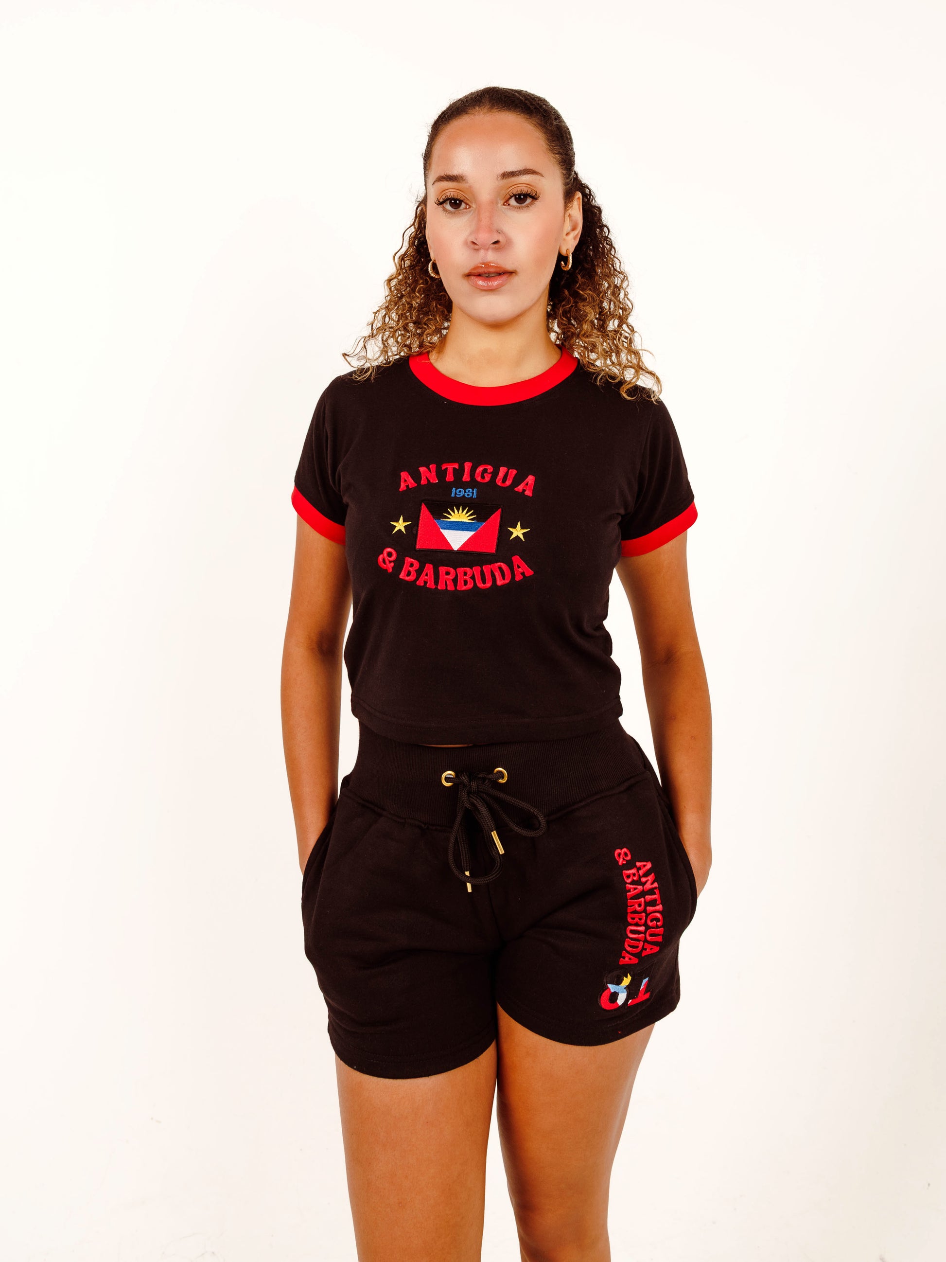 Woman wearing a black outfit with red accents featuring 'Antigua & Barbuda' on a white background