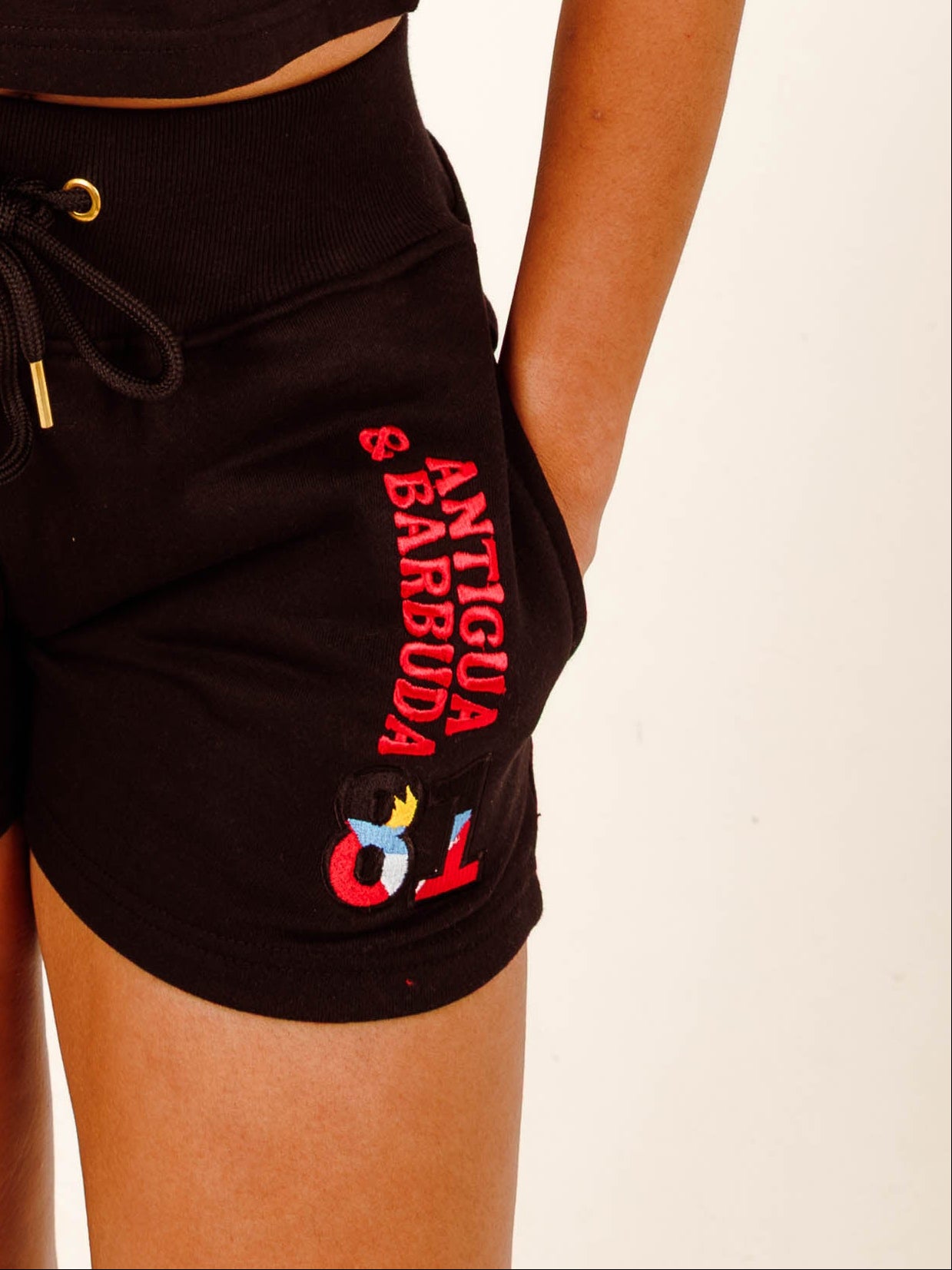 Person wearing a black 'Antigua & Barbuda' t-shirt and shorts set on a plain background